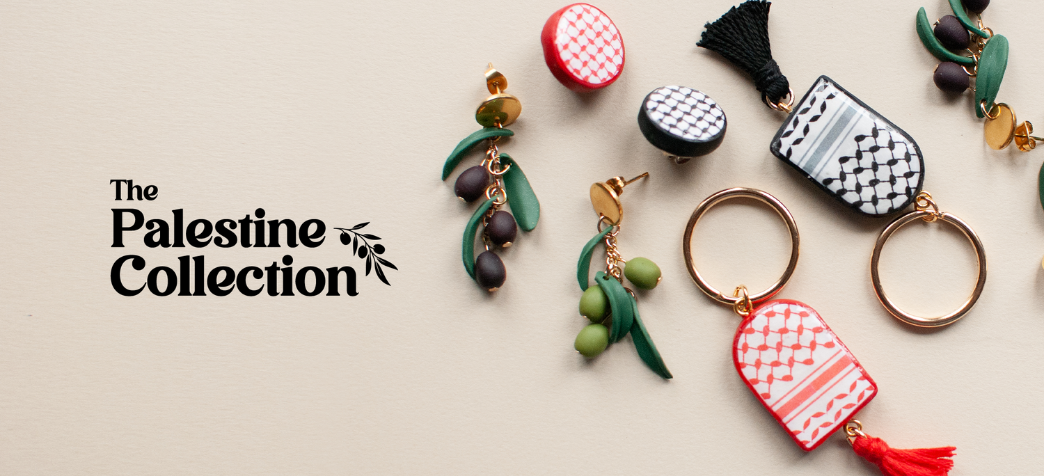 Text reads "The Palestine Collection" with several products spread around the photo. A pair of green and black olive branch earrings, a red and a black keffiyeh pin and a red and a black keffiyeh keychain